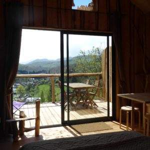 Cabane perchée en bois avec vue sur les montagnes et terrasse ensoleillée.