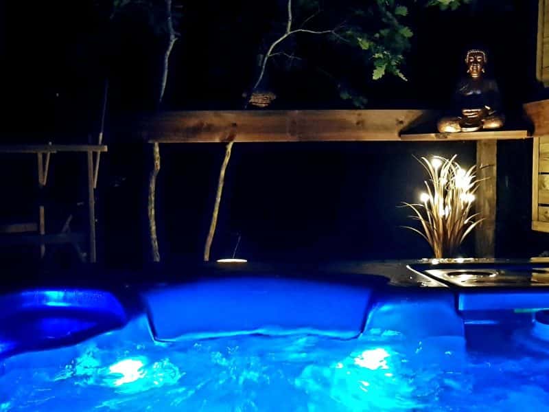 Hébergement en chalet avec jacuzzi illuminé, ambiance zen et nature environnante.