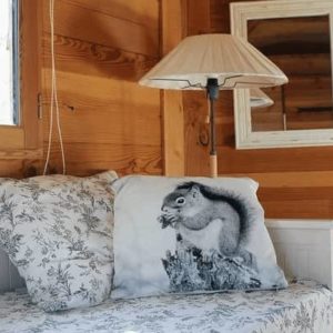 Cabane en bois avec un coussin écureuil et une lampe chaleureuse.