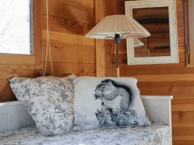 Cabane en bois avec un coussin écureuil et une lampe chaleureuse.