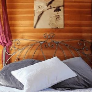 Chambre romantique en bois avec lit en fer forgé et coussins moelleux.
