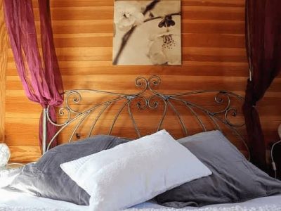 Chambre romantique en bois avec lit en fer forgé et coussins moelleux.