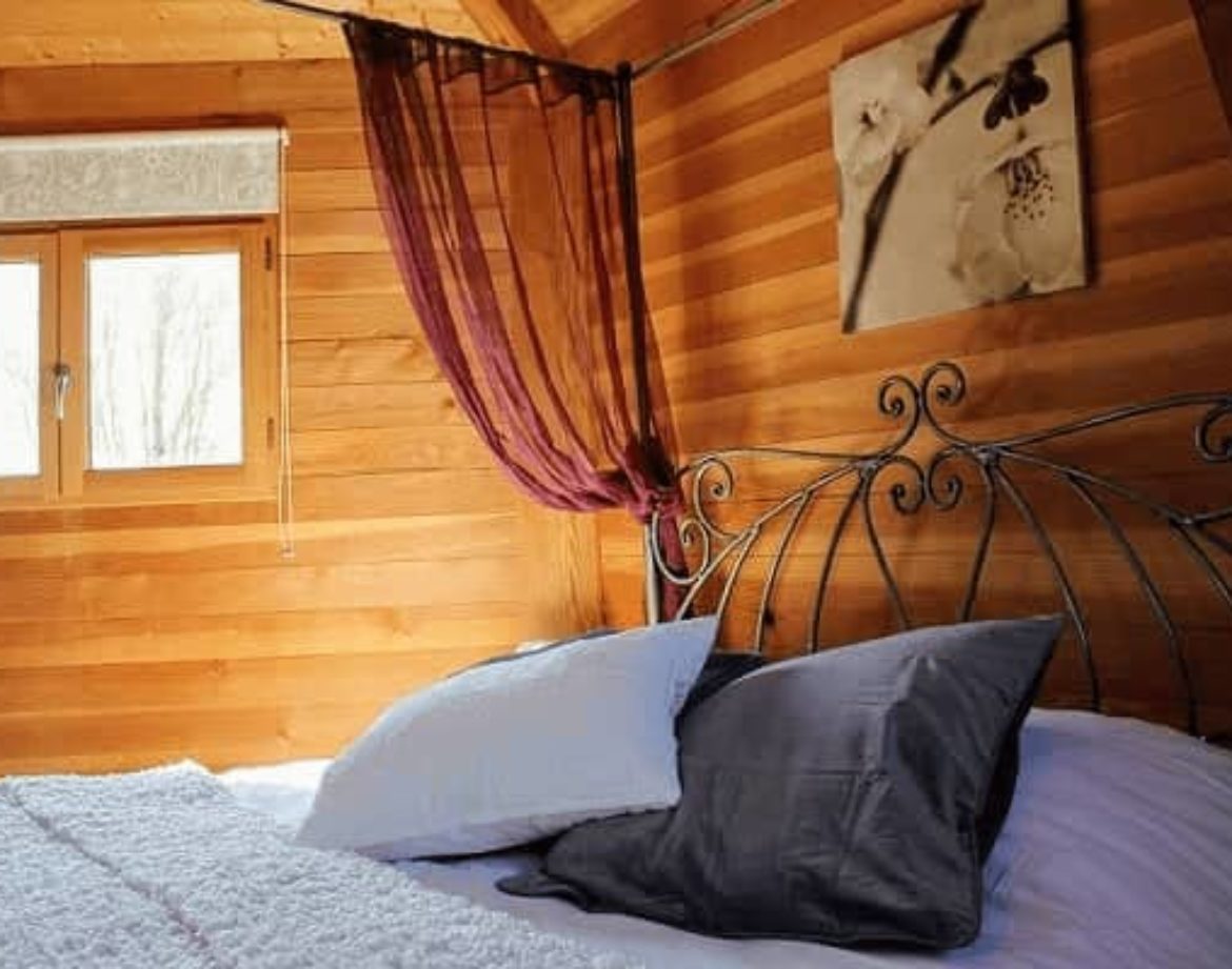 Chalet en bois chaleureux avec lit douillet et rideaux élégants.