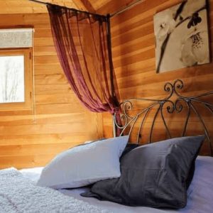 Chalet en bois chaleureux avec lit douillet et rideaux élégants.