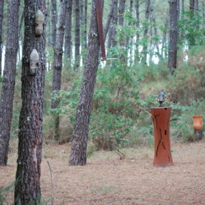 Hébergement insolite en Aquitaine, cabane dans les arbres entourée de pins et sculptures.