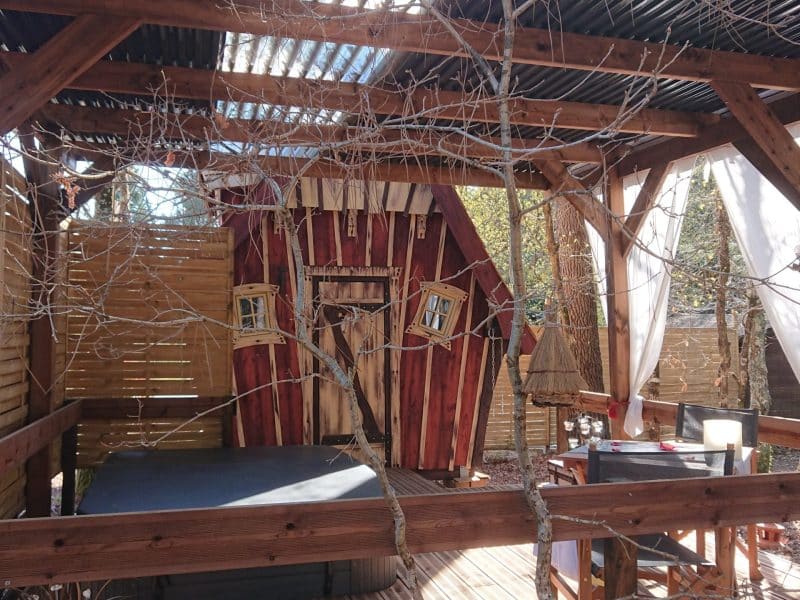 Cabane en bois avec jacuzzi, entourée de nature et décorée de détails charmants.