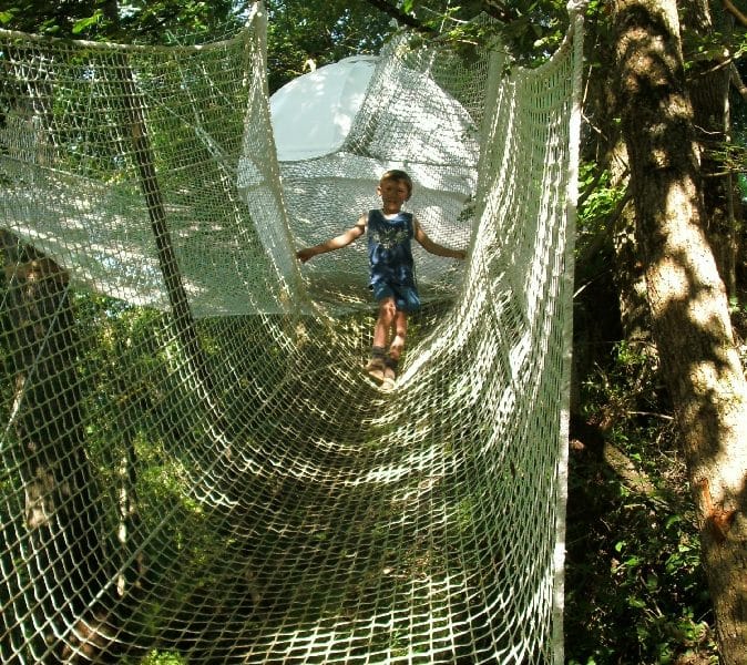 Cabane dans les arbres avec un filet suspendu, idéal pour les aventuriers.