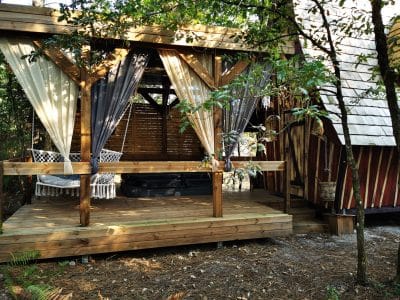 Cabane en bois avec terrasse, hamac et jacuzzi, nichée dans la verdure en Aquitaine.