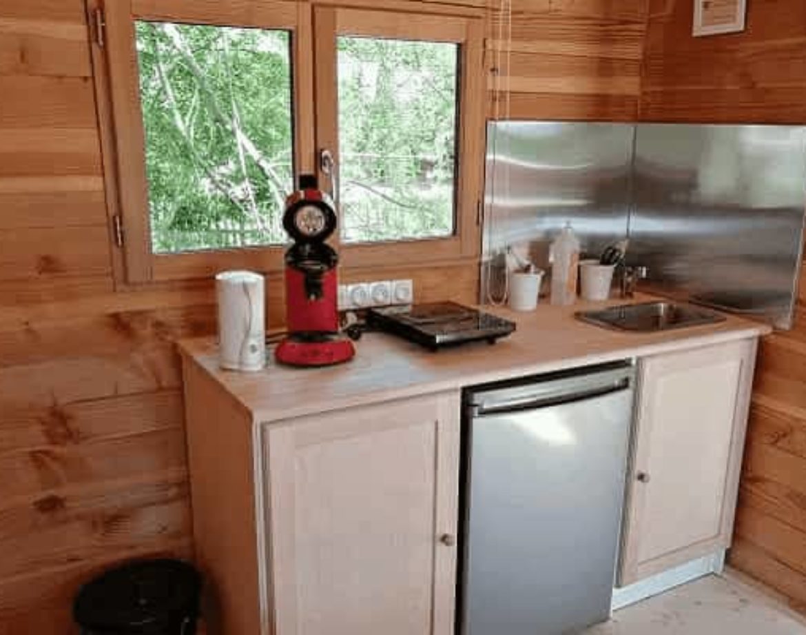 Hébergement insolite en bois avec cuisine équipée et vue sur la nature.