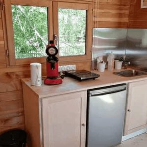 Hébergement insolite en bois avec cuisine équipée et vue sur la nature.