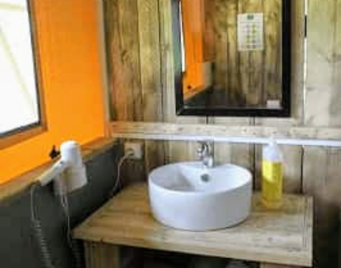 Salle de bain dun hébergement insolite en bois, avec lavabo moderne et décor chaleureux.
