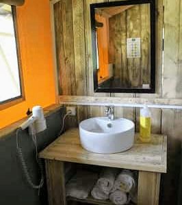 Salle de bain dun hébergement insolite en bois, avec lavabo moderne et décor chaleureux.