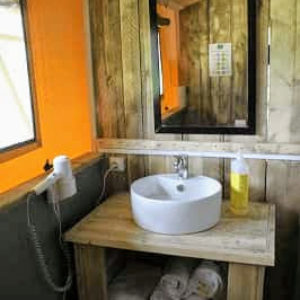 Salle de bain dun hébergement insolite en bois, avec lavabo moderne et décor chaleureux.