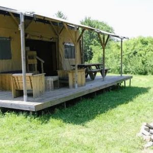 Tente safari spacieuse avec terrasse en bois, entourée de verdure. Parfait pour se ressourcer.