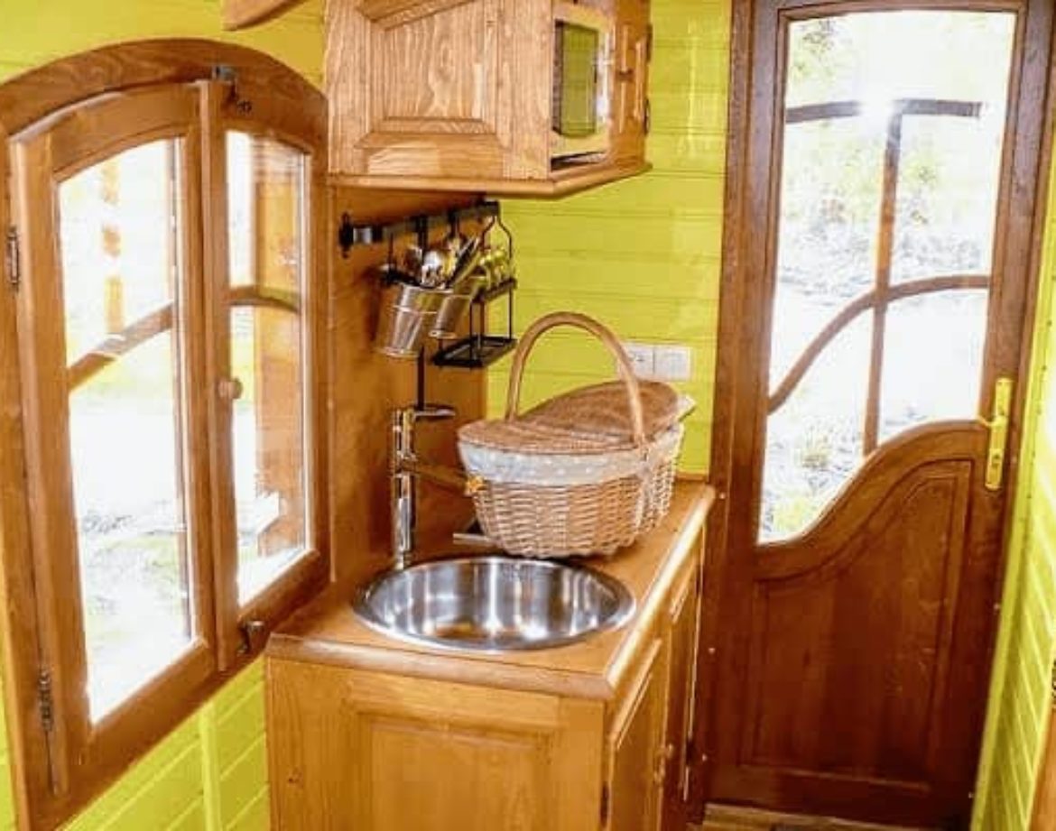 Hébergement insolite : intérieur dune cabane en bois avec murs verts vifs et cuisine équipée.