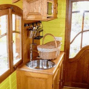 Hébergement insolite : intérieur dune cabane en bois avec murs verts vifs et cuisine équipée.