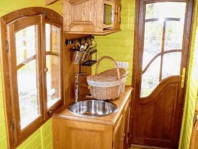 Hébergement insolite : intérieur dune cabane en bois avec murs verts vifs et cuisine équipée.