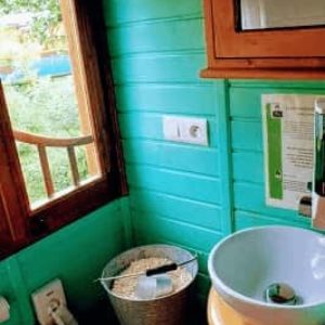 Cabane insolite avec murs turquoise et lavabo design, ambiance chaleureuse.