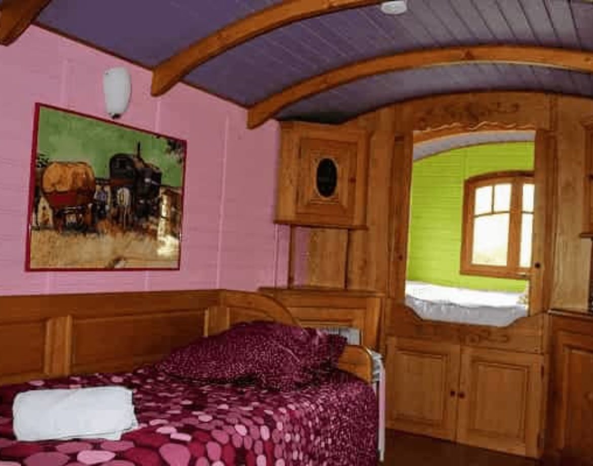 Chalet coloré avec lit douillet et décor en bois, ambiance chaleureuse et originale.