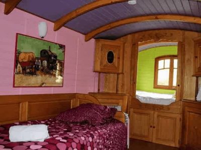 Chalet coloré avec lit douillet et décor en bois, ambiance chaleureuse et originale.