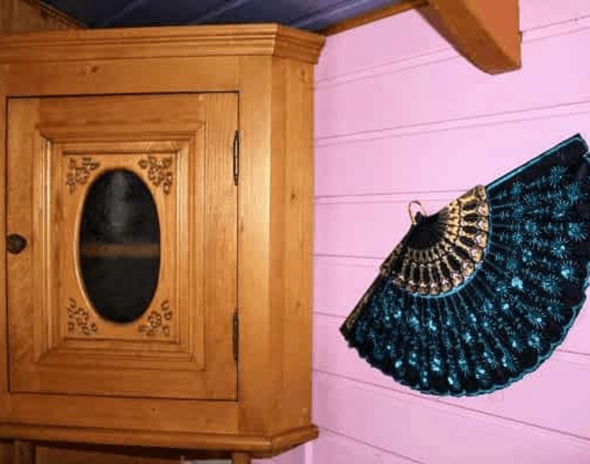 Hébergement insolite en bois avec un meuble vintage et un éventail décoratif.