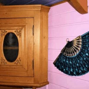 Hébergement insolite en bois avec un meuble vintage et un éventail décoratif.