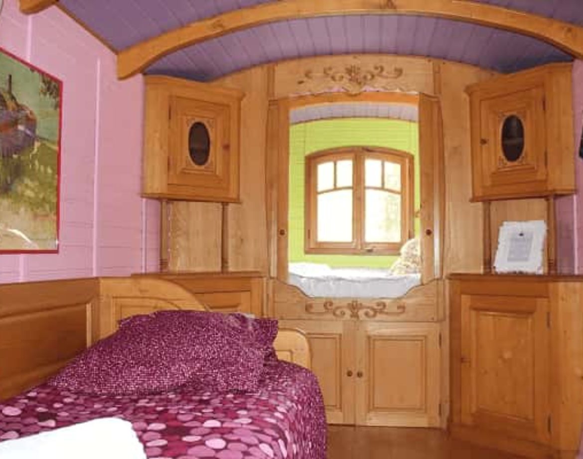 Chalet en bois coloré avec lit douillet et décor chaleureux. Parfait pour un séjour unique.