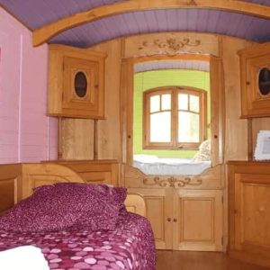 Chalet en bois coloré avec lit douillet et décor chaleureux. Parfait pour un séjour unique.