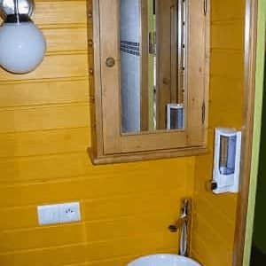Cabane en bois colorée avec un lavabo design et un miroir en bois.