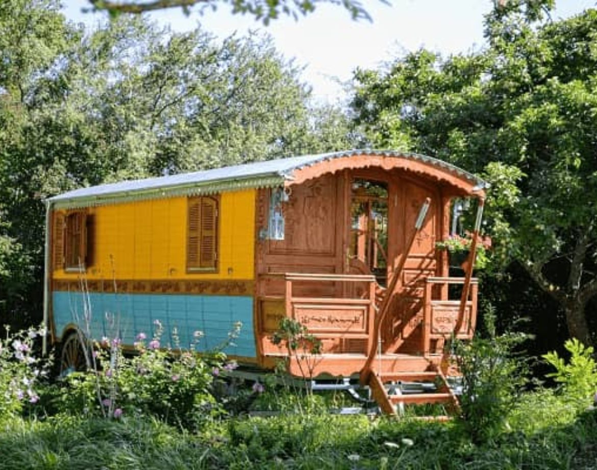 Charmante roulotte colorée entourée de verdure, idéale pour un séjour insolite.