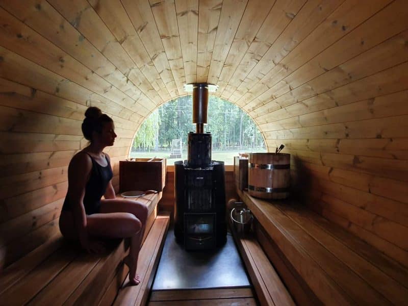 Hébergement en sauna en bois, avec vue sur la nature et un poêle central.