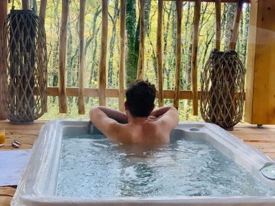 Cabane perchée en Aquitaine avec jacuzzi, vue sur la forêt verdoyante.