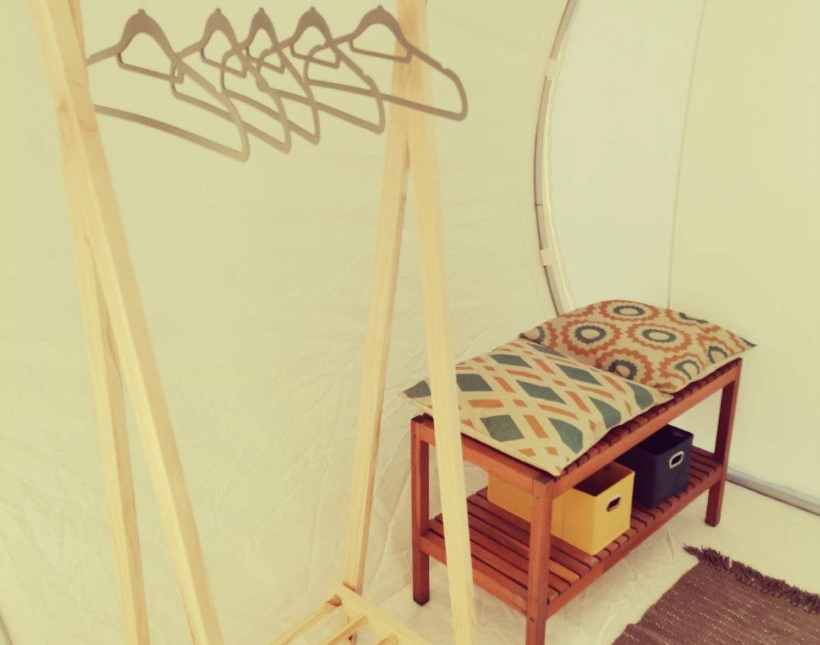 Hébergement insolite en bulle, avec porte-manteaux en bois et coussin coloré.