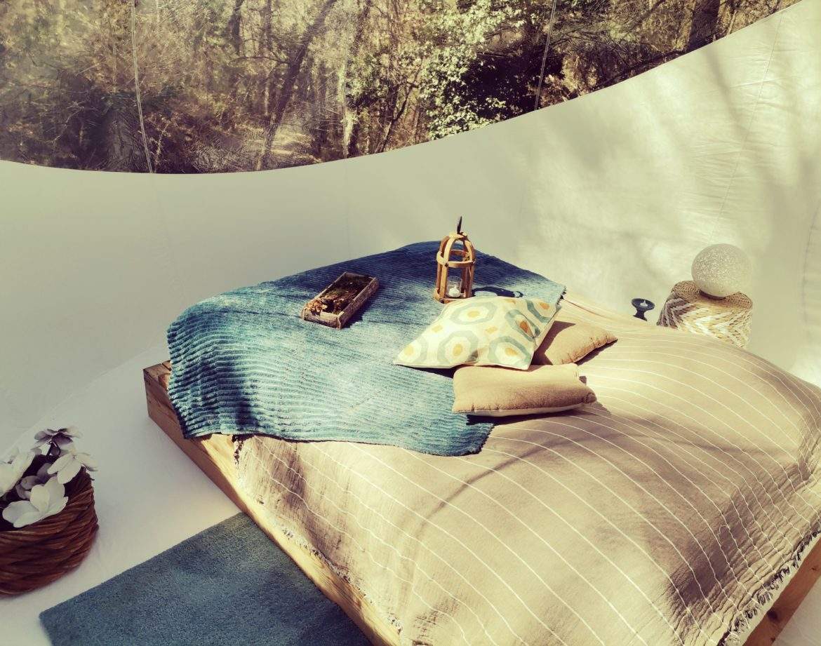 Chambre bulle en Provence, décor naturel avec lit douillet et coussins colorés.