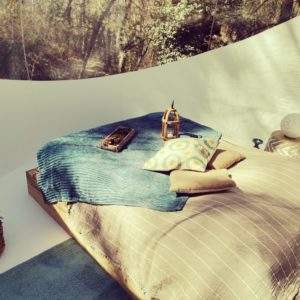 Chambre bulle en Provence, décor naturel avec lit douillet et coussins colorés.