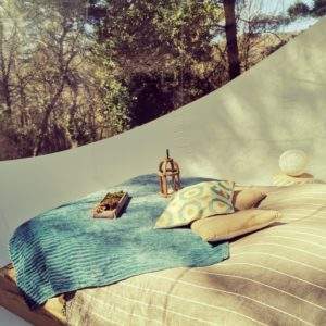 Hébergement insolite en bulle, lit douillet avec coussins colorés et vue sur la nature.