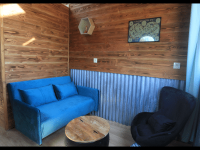 Hébergement insolite en Midi-Pyrénées : salon cosy avec canapé bleu et murs en bois.
