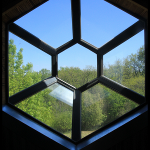 Hébergement insolite en Midi-Pyrénées avec vue panoramique à travers une fenêtre hexagonale.