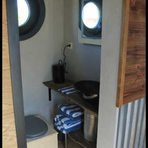 Hébergement insolite à Midi-Pyrénées : intérieur moderne avec lavabo et fenêtre ronde.