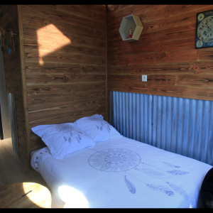 Chalet en bois avec lit douillet et décoration en métal, ambiance chaleureuse.