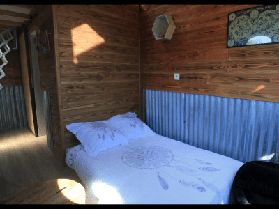 Chalet en bois avec lit douillet et décoration en métal, ambiance chaleureuse.