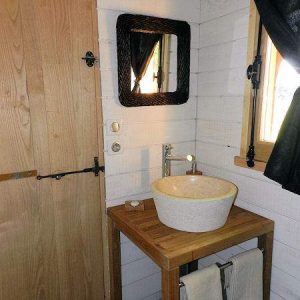 Salle de bain dun hébergement insolite en bois, avec lavabo en pierre et décor chaleureux.