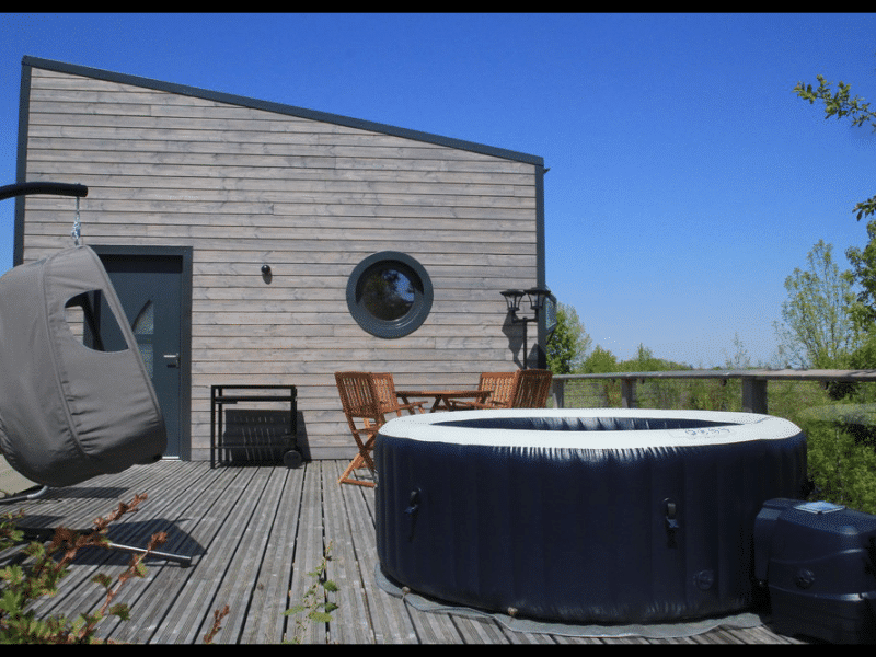 Hébergement insolite en Midi-Pyrénées avec jacuzzi sur une terrasse en bois.