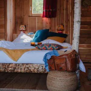 Chalet en bois chaleureux avec lit douillet et décor coloré, ambiance cosy.