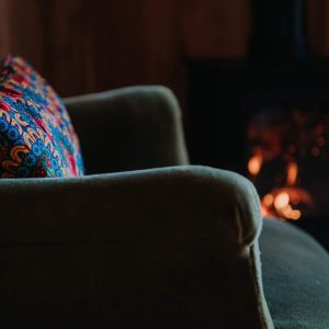 Canapé confortable avec coussin coloré près dun poêle à bois en Provence-Alpes-Côte dAzur.