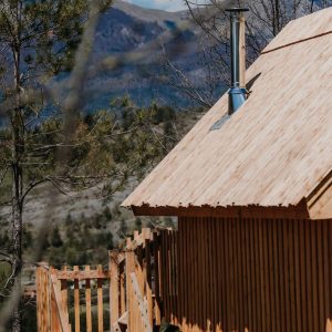 Cabane en bois perchée, avec un toit en tuiles et vue sur les montagnes.