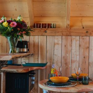 Hébergement insolite en bois avec une table élégante et des fleurs colorées.