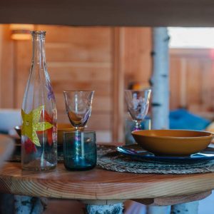 Hébergement insolite en bois avec vaisselle colorée et ambiance chaleureuse.