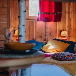 Chalet en bois chaleureux avec coussins colorés et lumière douce à Provence-Alpes-Côte dAzur.