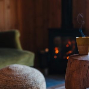Hébergement insolite en bois avec un coin salon chaleureux et une tasse fumante.